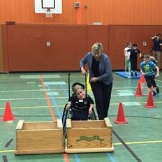 Kultusministerin mit Schüler im Rollstuhl im Sportunterricht