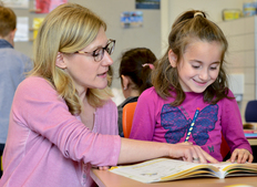 Lehrerin mit Schülerin und Lesebuch