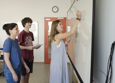 Junge Lehrerin mit zwei Schülern am Whiteboard