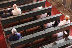Foto zeicht menschen mit Abstand in Kirche auf Bänke sitzend