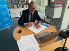 Graf Waldersee sitzt an einem runden Tisch mit aufgeklapptem Laptop und unterzeichnet den davor liegenden Vertrag