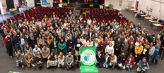 Gruppenfoto von oben in Aula mit Banner in der Mitte
