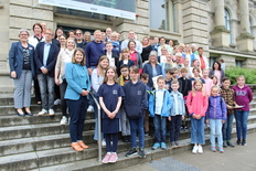 Schülerinnen, Schüler und Lehrkräfte der Plattdeutschen und Saterfriesischen Schulen mit der Kultusministerin auf einer Treppe