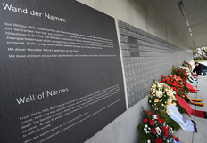 Wand der Namen der Opfer in Bergen-Belsen mit daran angelehnten Kränzen