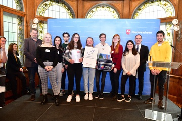 Schülerinnen und Schüler der Gesamtschule Schinkel mit Lehrer und Kultusminister Tonne und Urkunde auf der Bühne