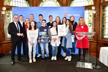 Schülerinnen und Schüler der Erich Maria Remarque Schule mit Lehrer und Kultusminister Tonne und Urkunde auf der Bühne