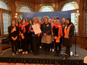 Gruppenfoto auf einer kleinen Bühne mit Ministerin und der Urkunde des Schülerfriedenspreises