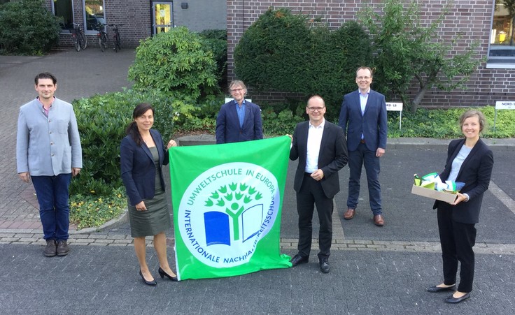 Foto, Gruppenbild draußen, Minister Tonne mit Koordinatoren im Netzwerk Europaschule, Zwei halten eine Flagge der Europaschulen