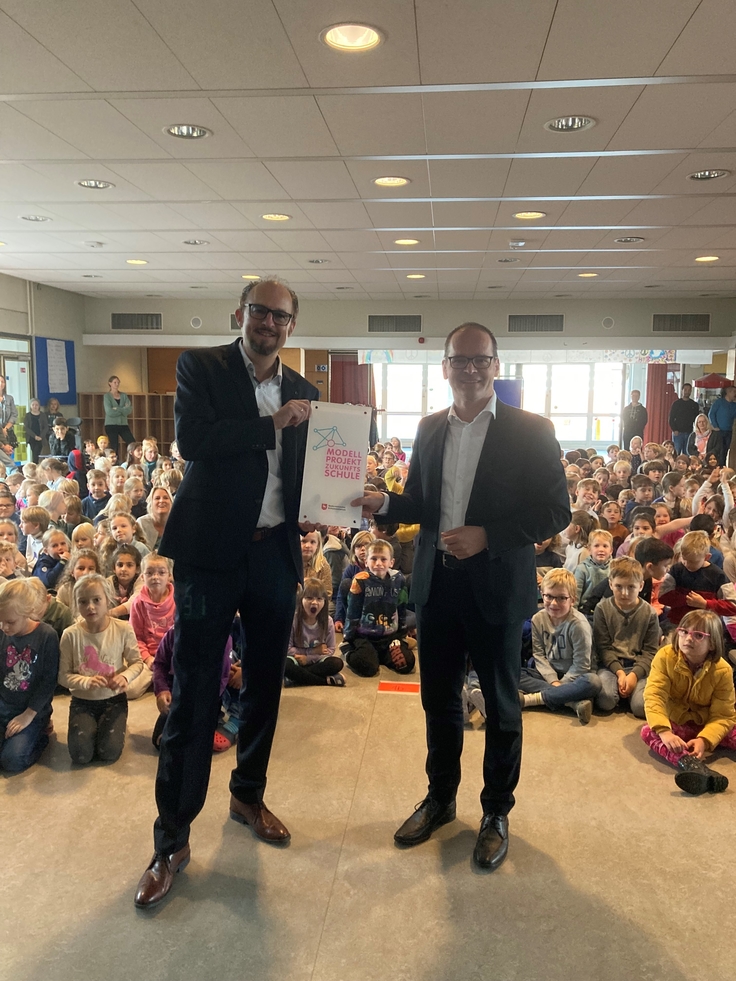Kultusminister Tonne überreicht Schulleiter Robert Kühn das symbolische Schild