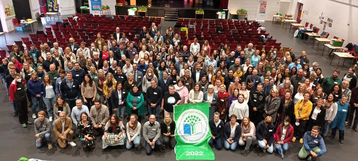 Gruppenfoto von oben in Aula mit Banner in der Mitte
