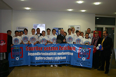 Minister Busemann mit Sportlern hinter dem blauen Banner 