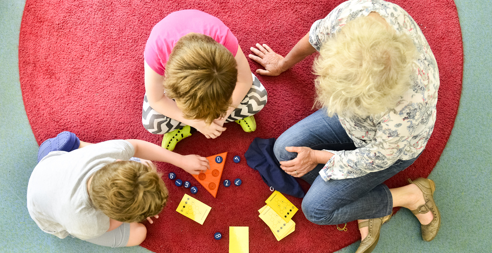 Lehrerin und zwei Kinder spiele auf dem Teppich