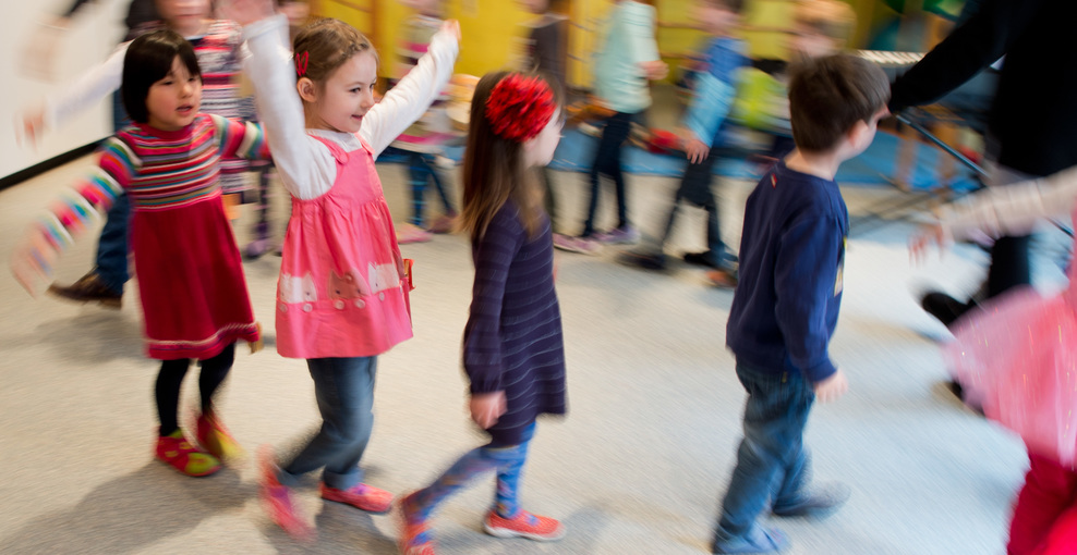 Kinder tanzen bei einer Musikstunde durch die Kindertagesstätte