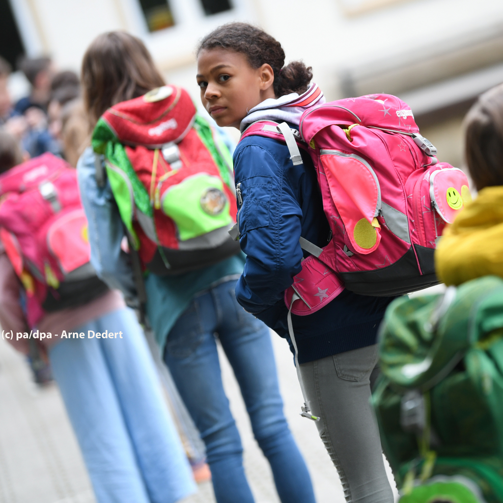 Kinder stehen mit Ranzen auf dem Schulhof
