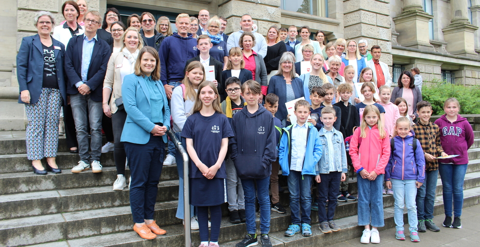 Schülerinnen, Schüler und Lehrkräfte der Plattdeutschen und Saterfriesischen Schulen mit der Kultusministerin auf einer Treppe