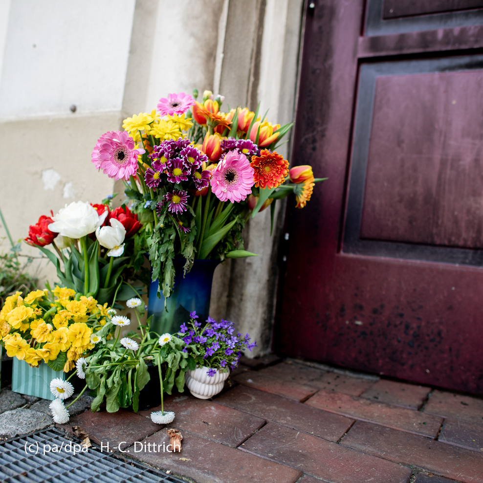 Blumen und Kerzen stehen vor einer Eingangstür