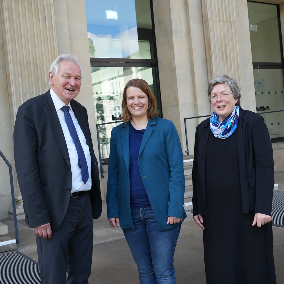 Drei Personen stehen vor einem ehrwürdigen Gebäude. Es ist der Landtag. Es sind ein Mann und zwei Frauen.