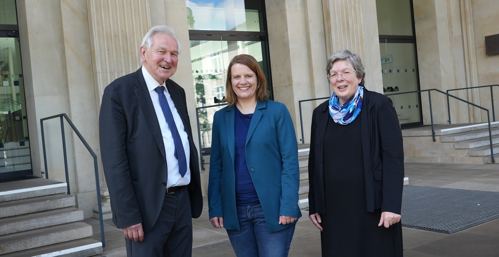 Drei Personen stehen vor einem ehrwürdigen Gebäude. Es ist der Landtag. Es sind ein Mann und zwei Frauen.